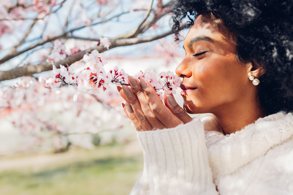 Women with curly hair smelling on blossom