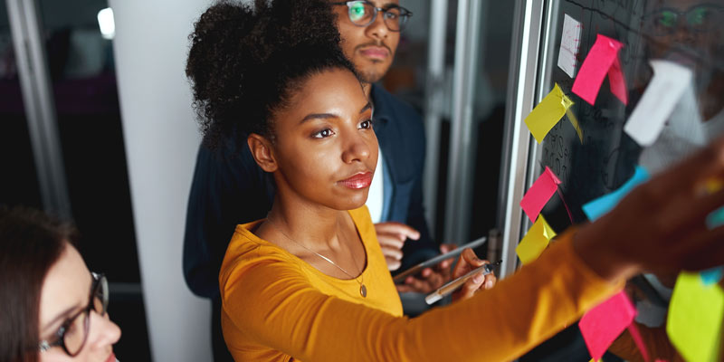 Woman sticks post-it to a wall