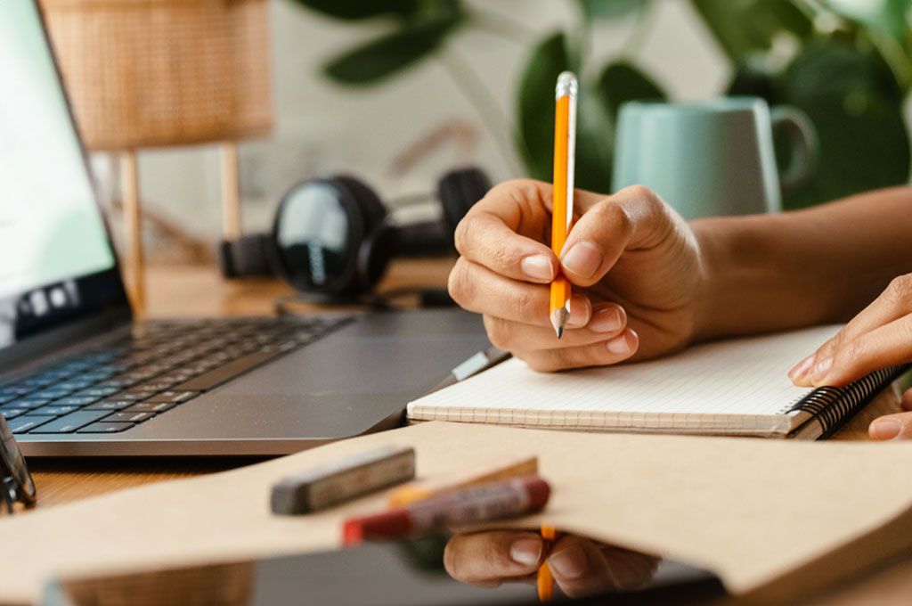 Laptop, somebody taking notes with a yellow pencil