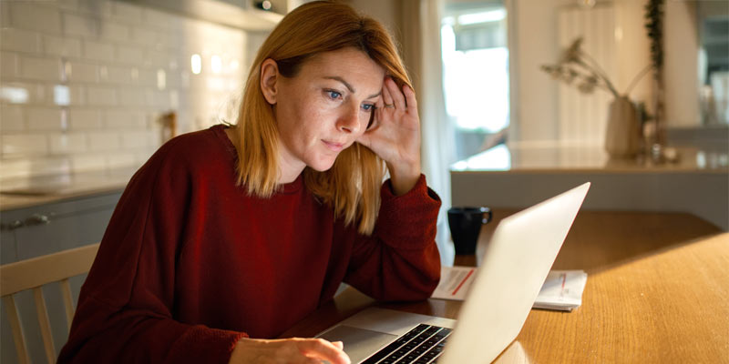 Blond Woman sitting in front of her Laptop with a concernd face